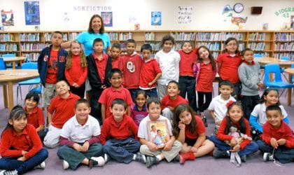 A group of children in red shirts and black pants.